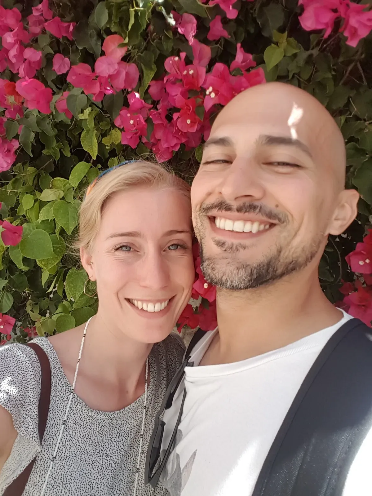 Anne and David smiling among bright pink flowers.