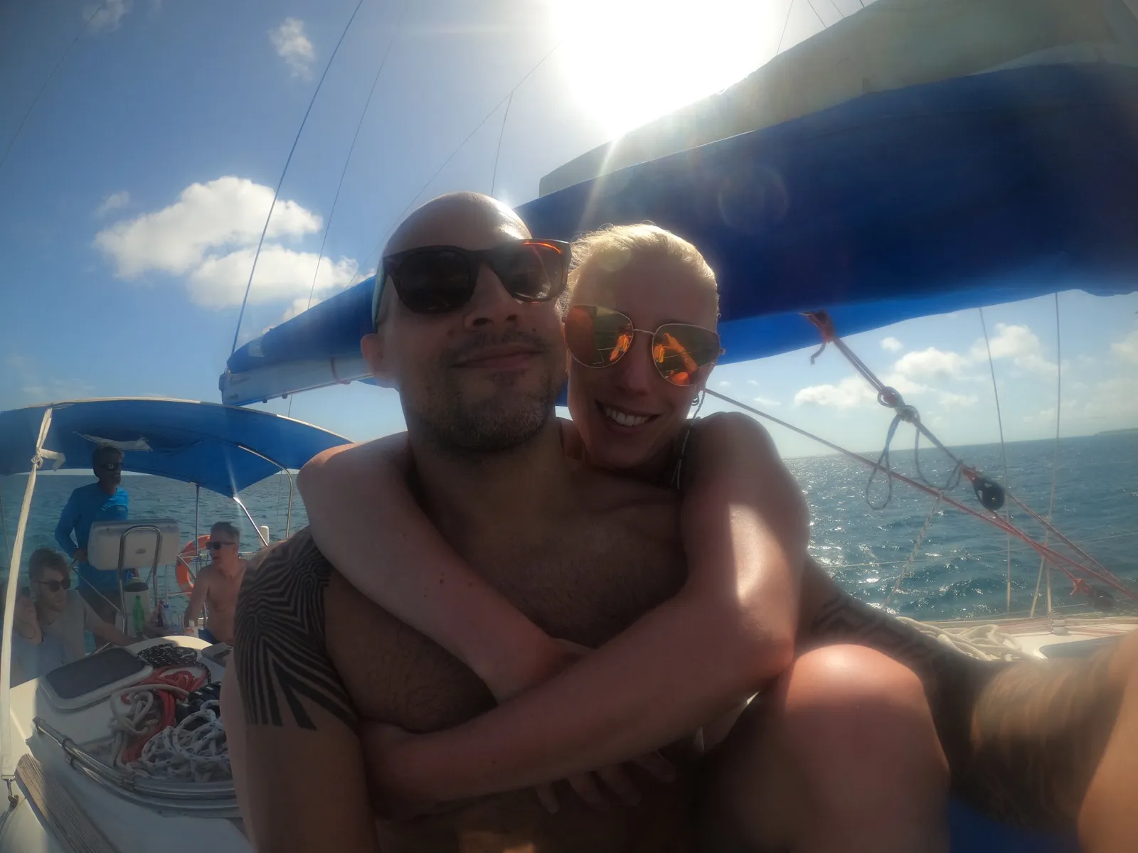 Anne and David hugging on a boat under bright sun.