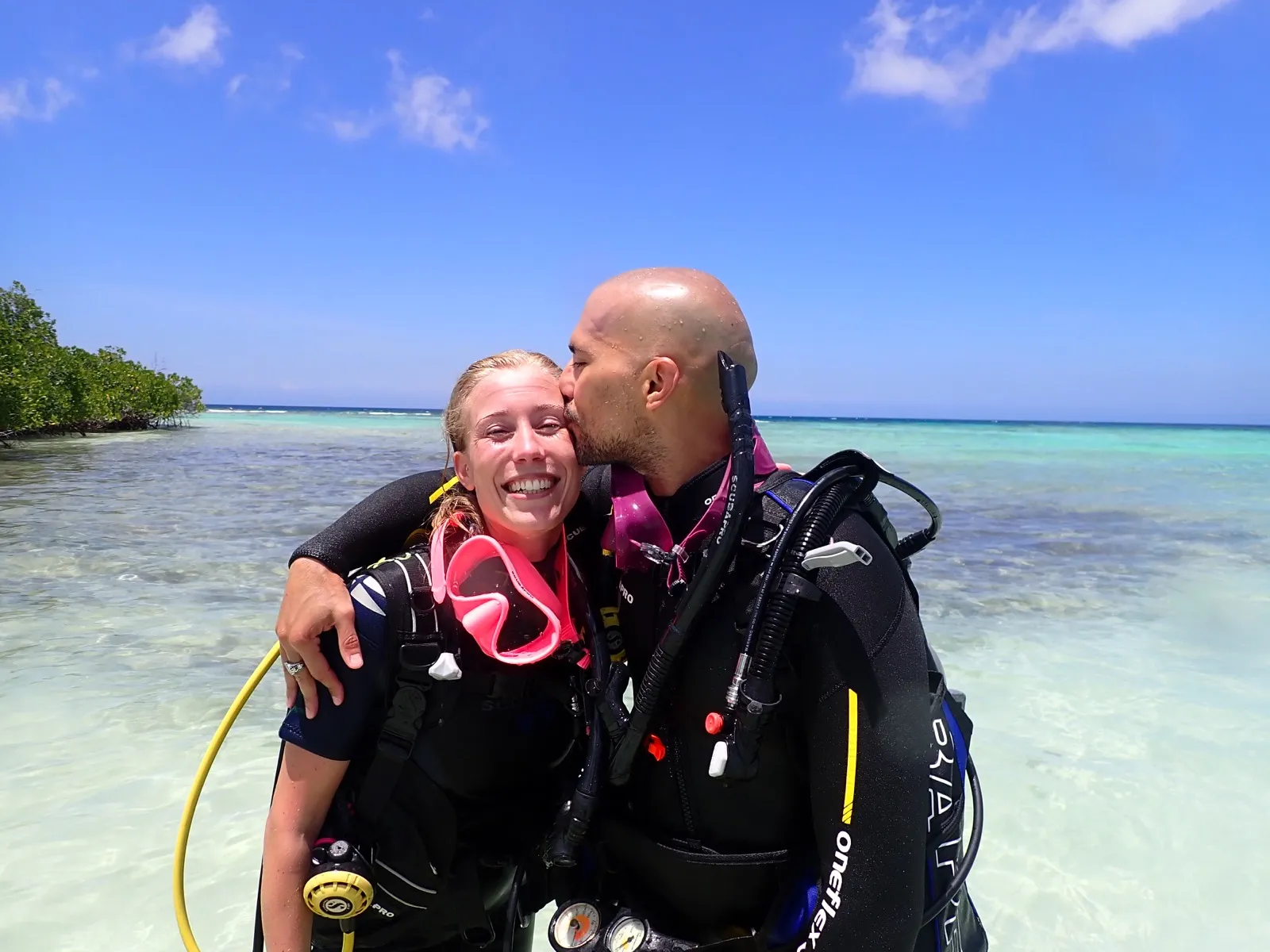 David kissing Anne on the cheek in scuba gear.