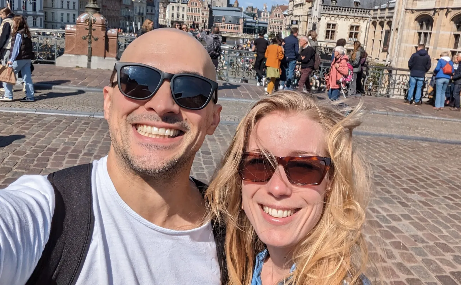 Anne and David taking a sunny city selfie on a bridge.